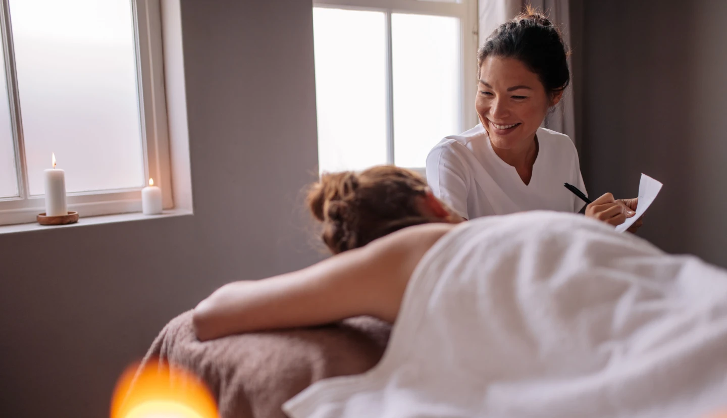 massage therapist talking to client laying on massage table